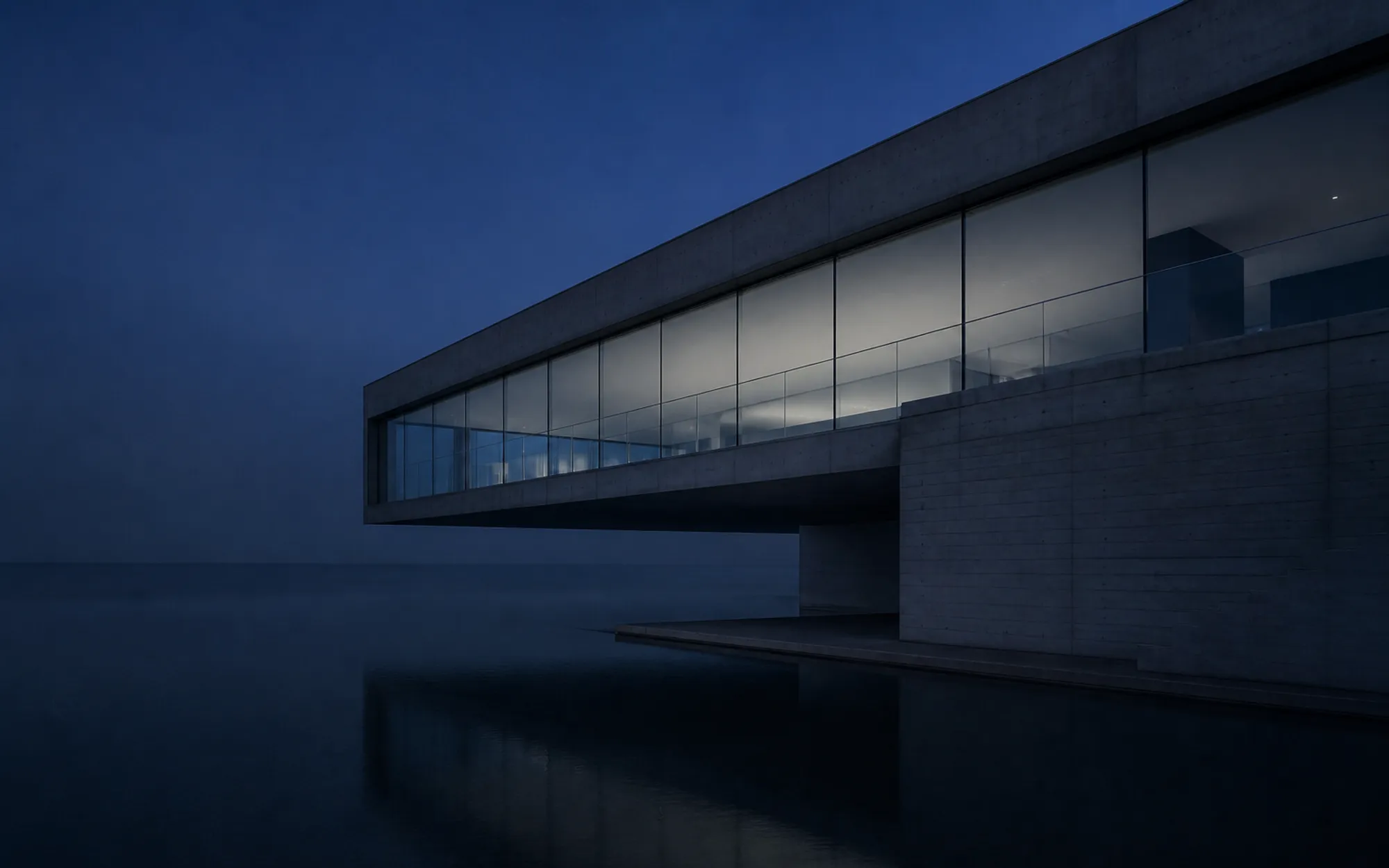 A long concrete and glass volume cantilevering over a dark reflecting pool at blue hour