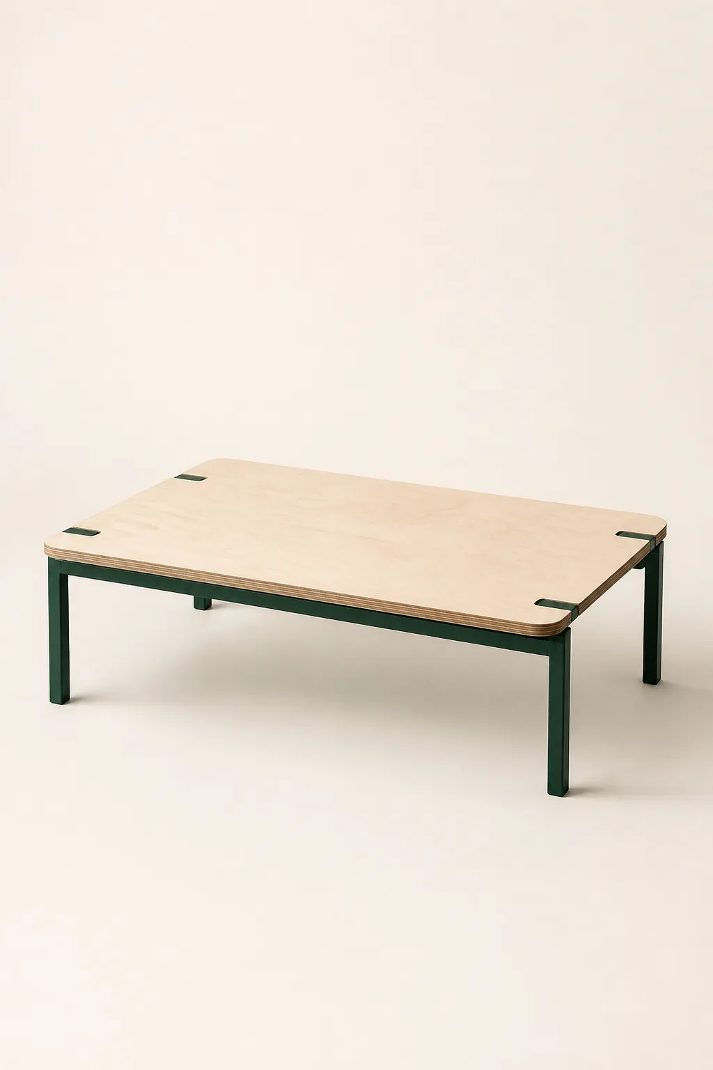 A low coffee table with a birch plywood top on deep green powder-coated steel legs