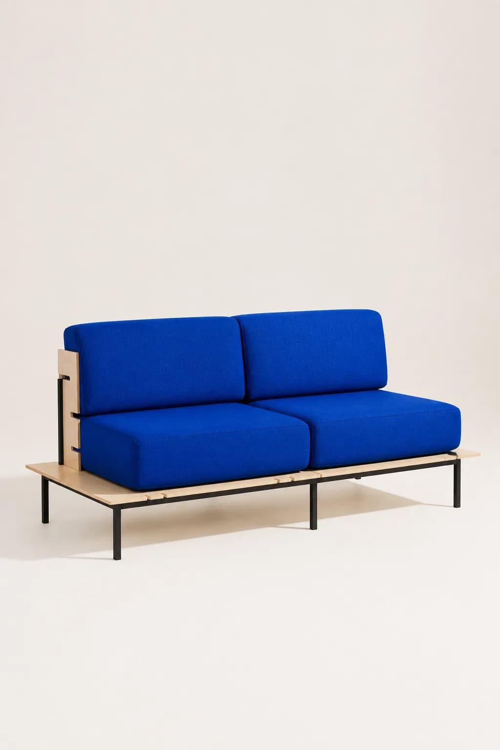 A two-seat modular sofa with cobalt blue wool cushions on a birch plywood platform