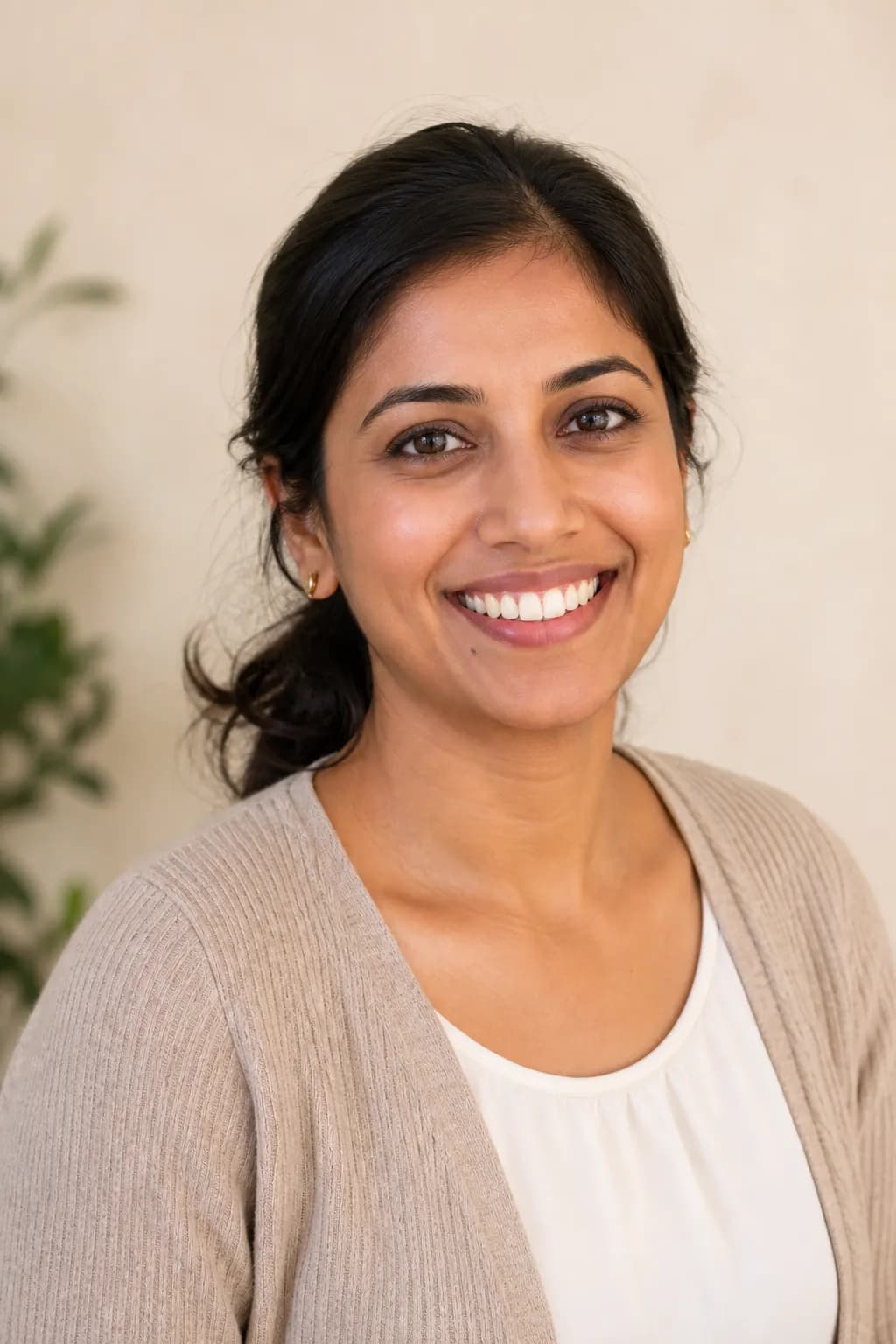 Priya, a dental hygienist with dark hair tied back, smiling brightly