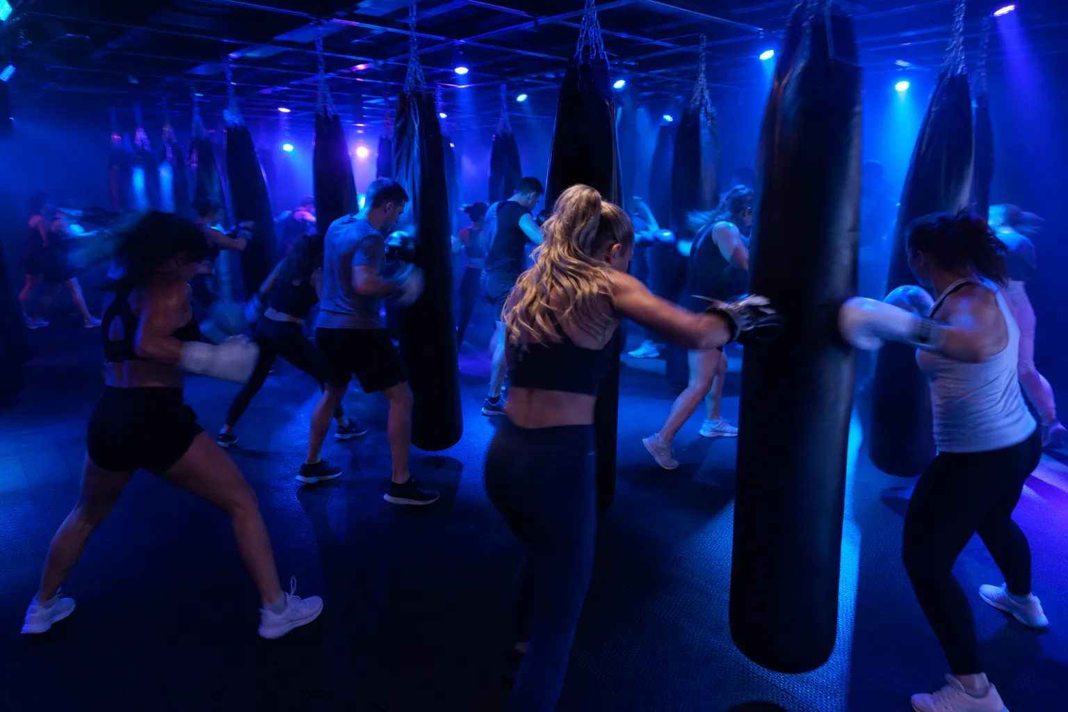 The gym at capacity mid-class seen from the back corner, everyone mid-swing