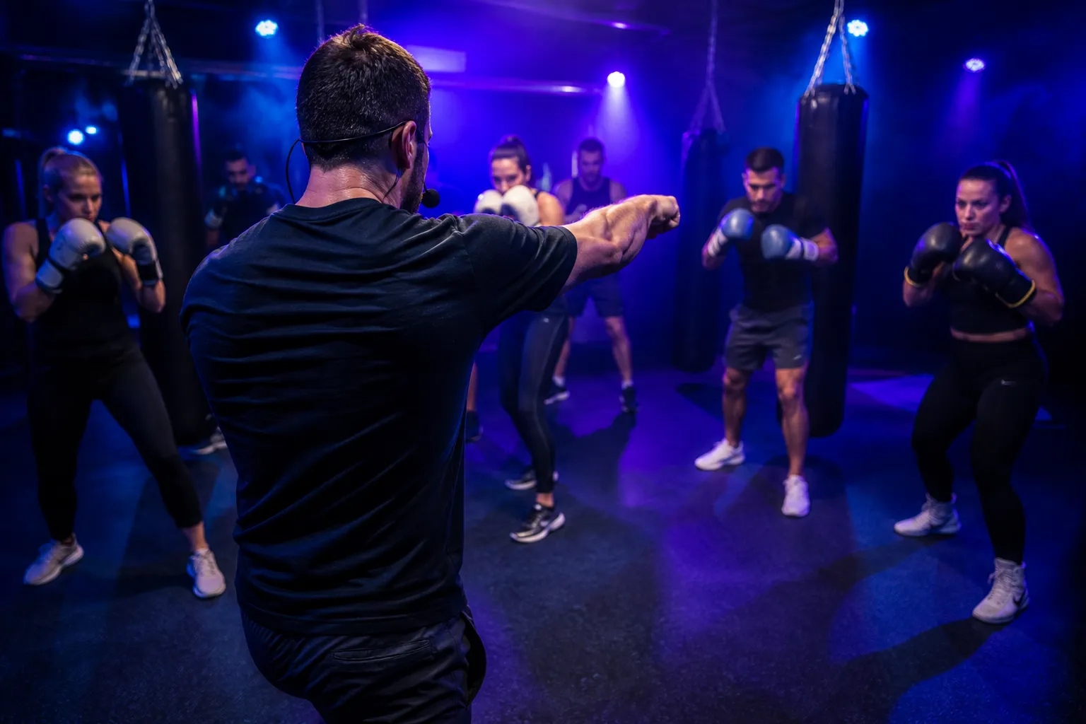 A coach seen from behind demonstrating a jab to a semicircle of class members