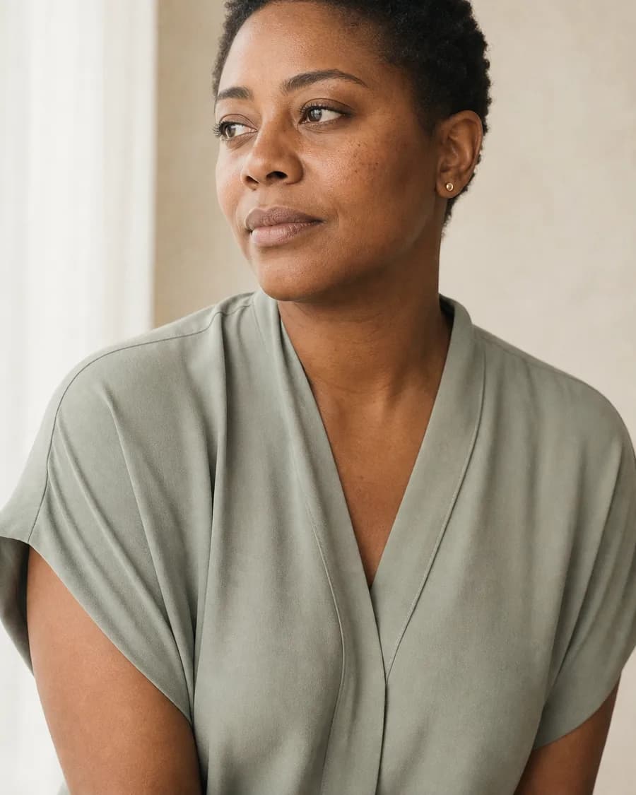 A portrait of a woman with short natural hair, in a sage tunic