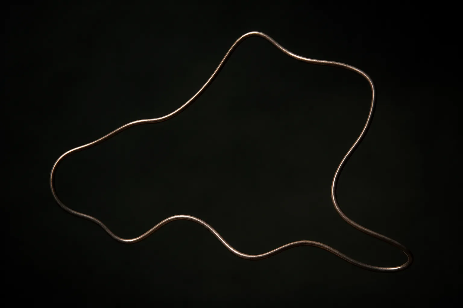 A single line of dark bronze wire bent into an open loop against darkness