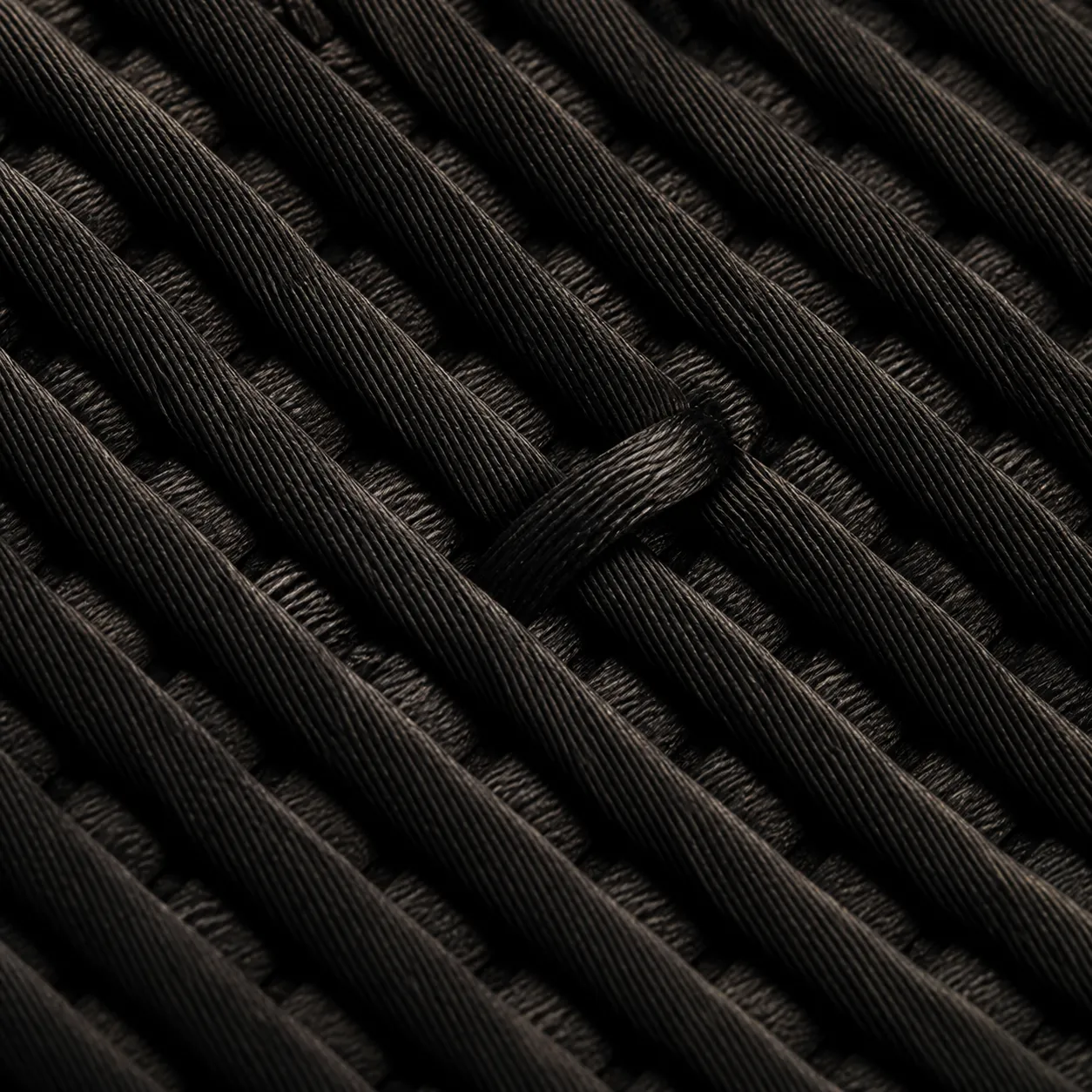 Woven black textile threads in strict diagonal order, one thread out of place