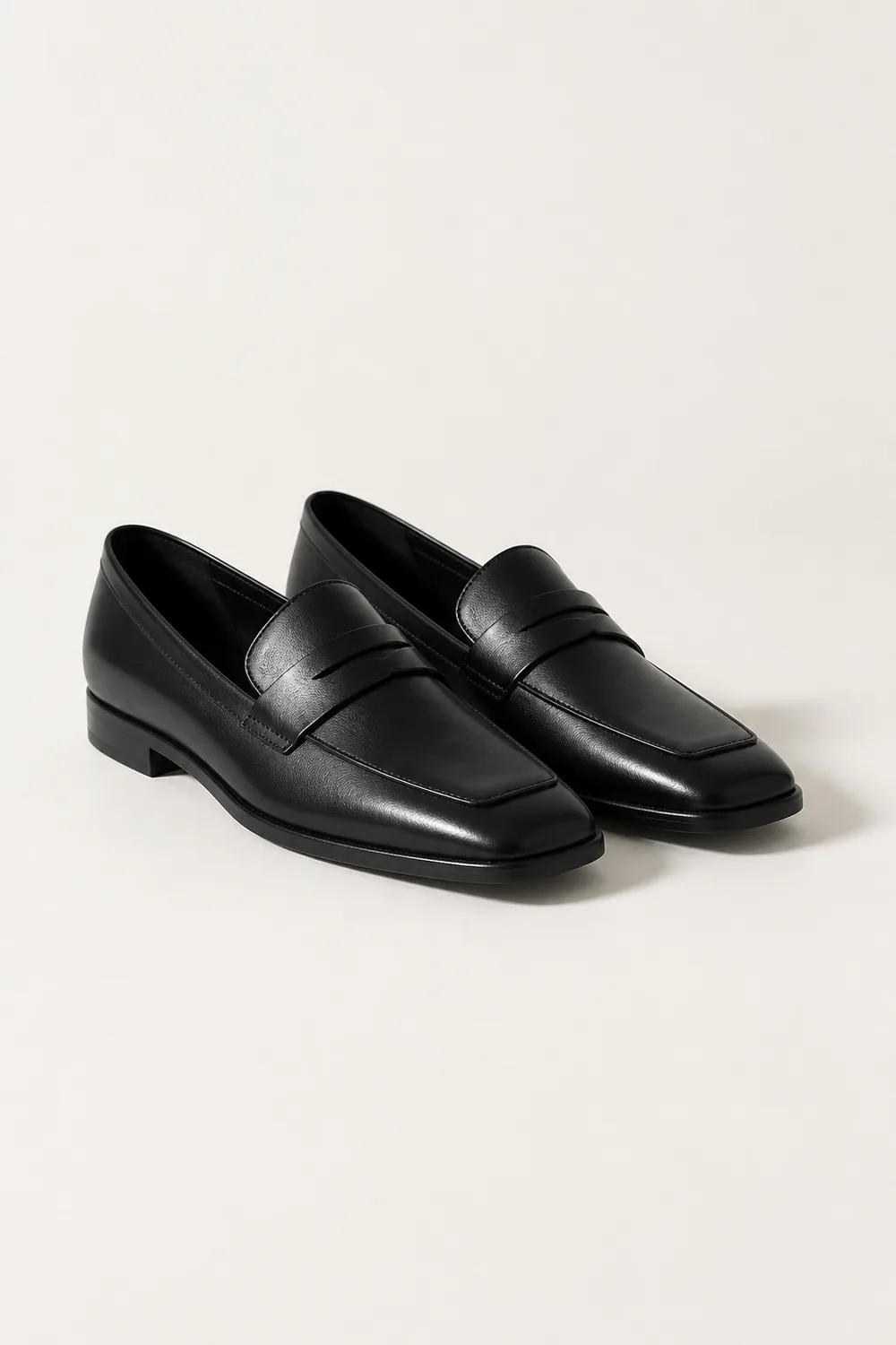 Pair of black leather loafers with a squared toe, low stacked heel and a plain keeper strap